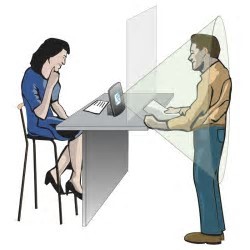 A woman sitting at a desk talking with a man standing with a counter between them. The portable loop is on the counter between the woman and man.